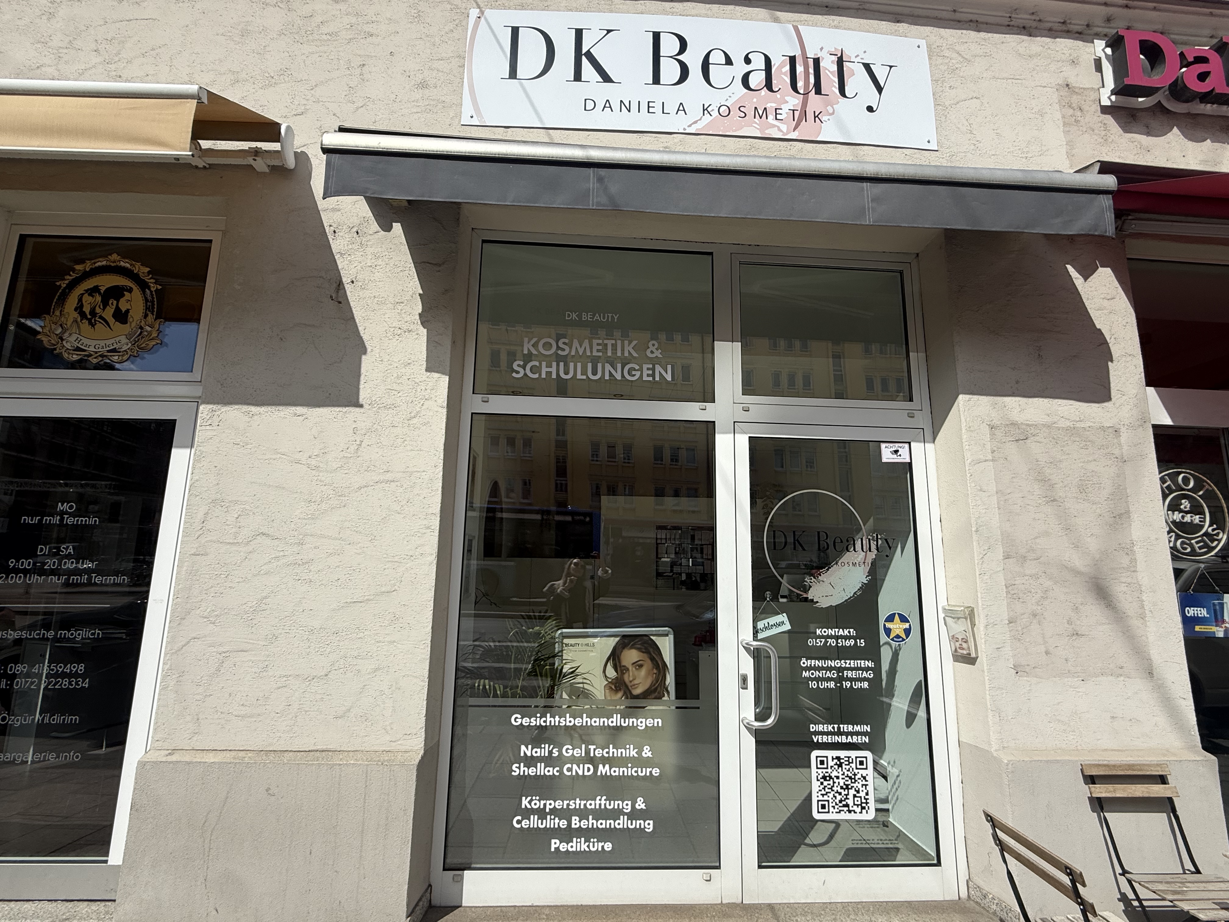 Eingang zu einem Kosmetikstudio mit Glasfront, Beschilderung und Werbeplakaten
